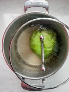 head of cabbage in pot of water with the lid flipped to prevent the cabbage from bobbing up and down - to keep it in place