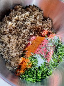 bowl of raw pork and beef, parsley, tarragon, thyme, onion, fresh garlic, hot Hungarian paprika, and cooked rice