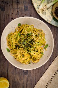 Asparagus Pesto Pasta with Minty Sugar Snap Peas in a matte speckled stone bowl on a brown wooden surface
