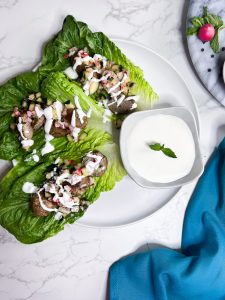 Lamb Kofta lettuce wraps with creamy feta-yogurt dressing Ingredients on a gray and white surface served family style