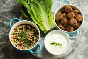 Lamb Kofta lettuce wraps with creamy feta-yogurt dressing Ingredients on a gray and white surface served family style