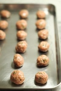 Lamb Kofta formed meatballs on a stainless-steel sheet baking pan before baking in the preheated oven