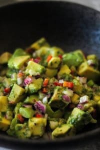 Avocado Salsa with fresno chile peppers, red onion, cilantro, and lime juice in a black bowl