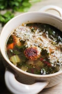 easy Italian wedding soup recipe in a while bowl with rounded handles on a light brown surface