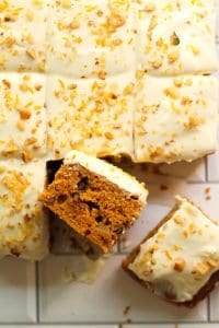 Close up of pumpkin Cake with orange cream cheese frosting cut into squares.