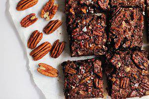 Overhead shot of pecan shortbread bars on a piece of parchment paper and pecans on the side.