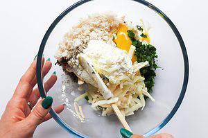 stuffed mushrooms with crab ingredients being stirred together in a glass mixing bowl.
