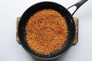 Panko breadcrumbs being toasted in a nonstick skillet.