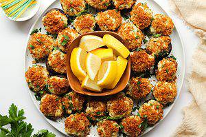 Stuffed mushrooms with crab on a white plate, with toasted brown breadcrumbs on top.