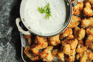 crispy cauliflower bites with a side of homemade buttermilk ranch dressing on a silver tray lined with paper.