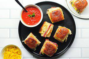 Air fryer Italian sliders on a black plate with a side of marinara sauce.