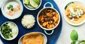 Chorizo Breakfast Tacos with Cilantro Lime Crema ingredients in separate bowls in a blue platter, with one single taco on a side plate.