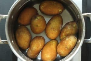 A silver stainless steel pot filled with water and potatoes.