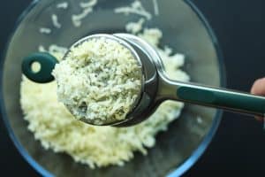 Close up of cooked potatoes being pressed through a ricer.