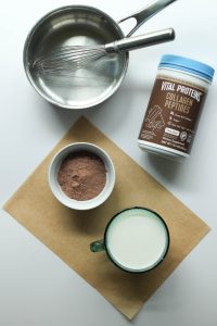 Protein hot chocolate ingredients: container of Vital Proteins collagen powder, and 1 1/2 cups of milk.