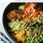Assembled shrimp poke bowl in a black round bowl with blue and white wooden chop sticks on a white surface.