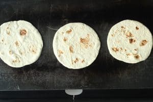 Tortillas for fried chicken tacos warming on an electric skillet.