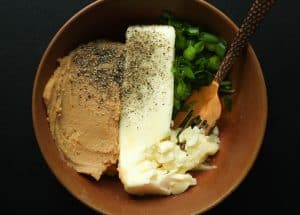 Miso butter ingredients in a brown bowl on a black surface.