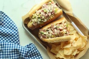 Chopped Italian sub sandwich on a silver tray lined with parchment paper with chips and a checkered picnic napkin.