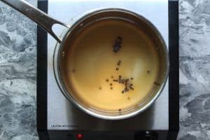 A pot with vinegars, water, sugar, salt, and black peppercorns on a heating surface.