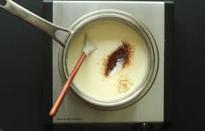 Chicken crunch wrap Mexican queso with seasonings not yet mixed in a stainless steel pot with a wooden spoon.