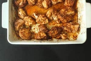 Cooked and taco-seasoned chicken breast pieces in a white baking dish on a black surface.