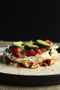 Chicken crunch wrap ingredients stacked on a burrito-sized tortilla before being wrapped.
