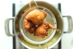 Close up of applesauce fritters draining in a small fine mesh strainer.