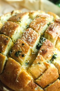 Close up of stuffed garlic bread with cheese cut in a checkerboard-style and topped with shredded parmesan.