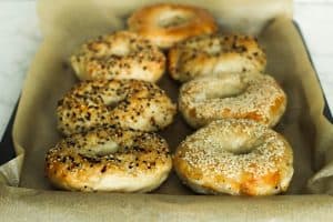 Homemade everything and sesame seed bagels on a parchment lined baking sheet.