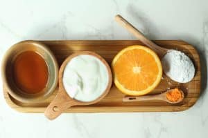 Maple syrup, Greek yogurt, powdered sugar, orange zest, and half an orange for yogurt glaze/drizzle on wooden board.