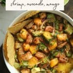 Summer salad recipes - shrimp, avocado, and mango salad in a bowl on a cutting board with tostadas.