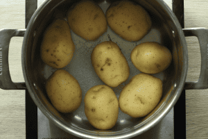 A pot of water and salt with Yukon gold potatoes for potato salad with dill pickles.