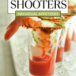 Individual appetizers shrimp cocktail shooters in shot glasses with a slice of cucumber and sprig of dill on a white plate with ice.