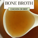 A close up of a big white spoon holding homemade bone broth over a bowl of broth.