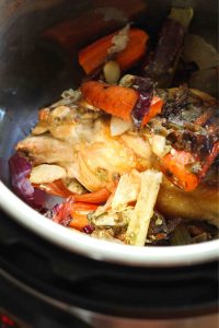 Veggie scraps and a chicken carcass in and Instant Pot.