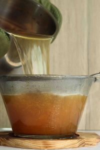 Golden turmeric turmeric concentrate being poured into a glass bowl for cooking or health remedies.