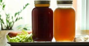Homemade bone broth with both beef and chicken broth in mason jars glowing golden from the sunlight shining in.