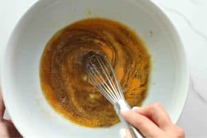 Eggs being whisked into the sugars and avocado oil for carrot cake loaf cake.