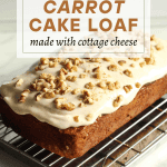 Healthy dessert recipes carrot cake loaf with cream cheese and cottage cheese frosting topped with walnuts on a cooling rack.