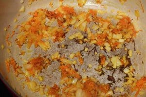 Carrots, onions, and garlic being sauteed in a dutch oven.